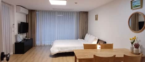 Ein Hotelzimmer mit Bett, Schreibtisch, Stuhl, Fernseher und Spiegel.