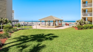 A gazebo with a view of the ocean, surrounded by well-maintained grass and plants. - Castle Reef 128 Walk to the Ocean (New Smyrna Beach)