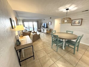 A spacious living area with a dining table, chairs, a sofa, and a television.