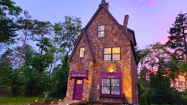 Un bâtiment en pierre avec une porte et des fenêtres violettes, portant les inscriptions « Chree Wizards » et « Bils & Bobs ».
