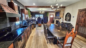 Une cuisine spacieuse dotée d’un grand îlot central, de meubles de cuisine en bois foncé et d’une cheminée en pierre.