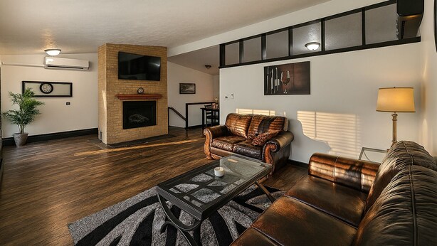 A living room with a fireplace, leather sofas, a coffee table, and a TV mounted on the wall. - Serene Family Home: Sleeps 16! (Wyoming)