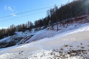 A snowy mountain slope with a ski lift and trees. - LES COLCHIQUES N°C208 (LES ORRES 1800)
