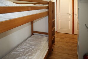 A bunk bed with white bedding, a wooden floor, and a white door in the background. - LES COLCHIQUES N°C208 (LES ORRES 1800)