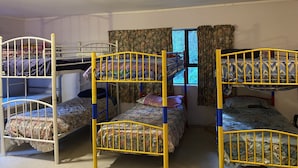 A dormitory room with bunk beds, a window with curtains, and a ceiling light fixture. - Bush paradise  (Auckland)