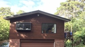 A two-story house with a garage, a balcony, and a deck. - Bush paradise  (Auckland)