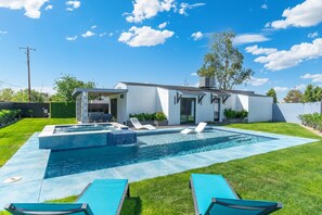 Une maison moderne dotée d’une piscine, d’un espace salon extérieur et d’une pelouse bien entretenue.