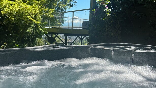 Un site de sources chaudes doté d’une terrasse en bois et offrant une vue sur une montagne en arrière-plan.