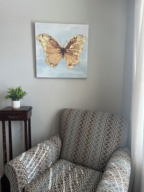 Relax in a stylish room with a patterned armchair, framed artwork, and a small side table.