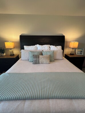 Restful retreat with a neatly made bed, two bedside tables, and a comfortable throw blanket.
