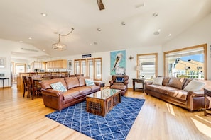 A spacious living room with leather sofas, a coffee table, and a large rug. - Wink Beach | Oceanfront | Private Pool, Hot Tub, and Dog Friendly (Nags Head)