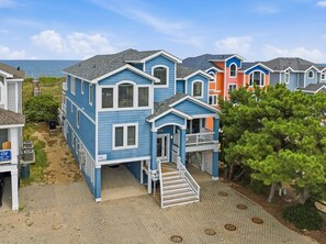 A coastal residential area with houses featuring a uniform architectural style, a paved driveway, and a view of the sea. - Wink Beach | Oceanfront | Private Pool, Hot Tub, and Dog Friendly (Nags Head)