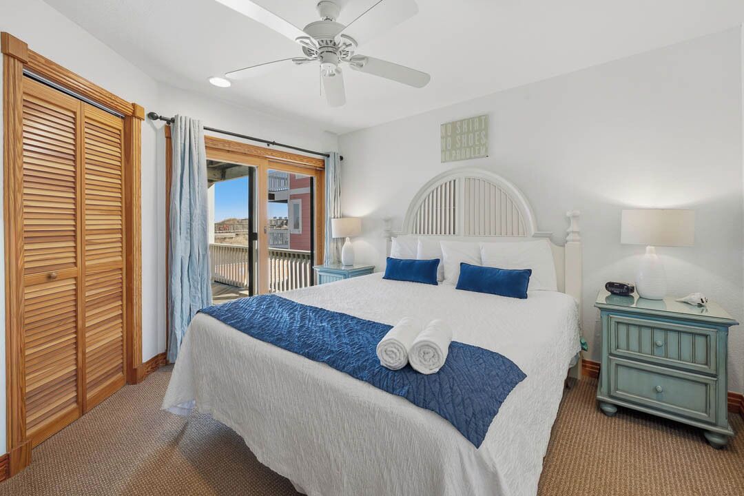 Une chambre d’hôtel avec un grand lit, un ventilateur de plafond, une table de chevet et une vue sur l’extérieur.