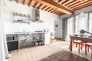 A modern kitchen with a built-in oven, microwave, and stainless steel shelves.