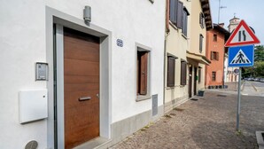 A building with a large wooden door, a small window, and a number '92' sign. - GuestHost - Jacaranda Comfy House (Udine)