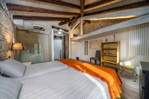 A bedroom with a large bed, a wooden ceiling, a glass shower, and a bookshelf.