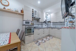 Une cuisine équipée d’un four à micro-ondes, d’une cuisinière, de placards et d’une horloge murale.