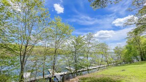 Een pad dat leidt naar een meer, met bomen aan beide zijden en een bank aan het water.