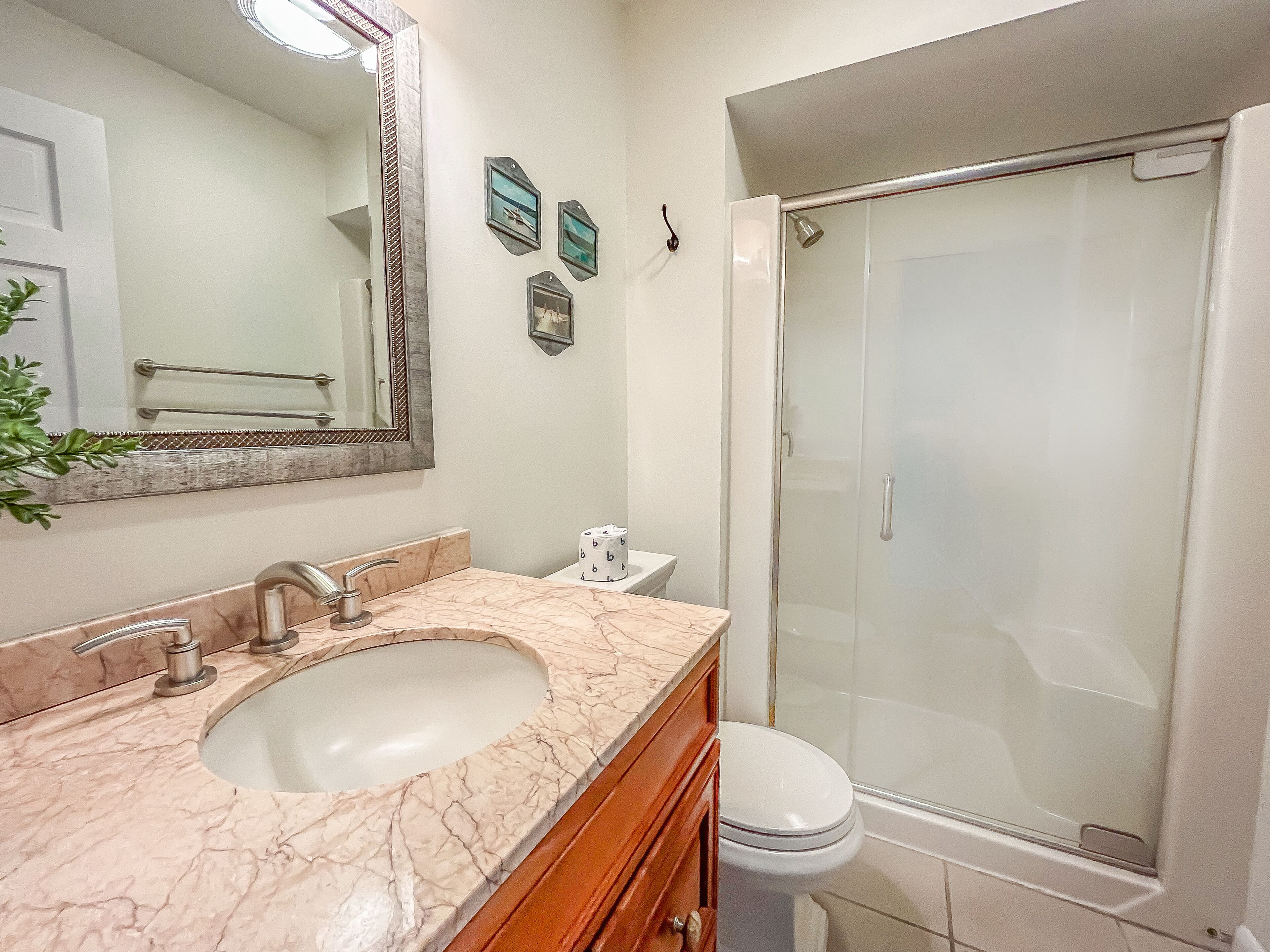 A bathroom with a marble sink, a toilet, a glass shower enclosure, and a mirror.