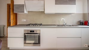 Una cocina moderna con horno empotrado, electrodomésticos de acero inoxidable y armarios blancos.
