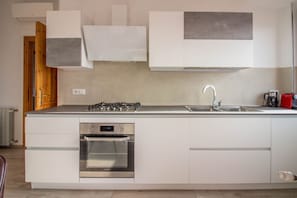 A modern kitchen with a built-in oven, stainless steel appliances, and white cabinetry.