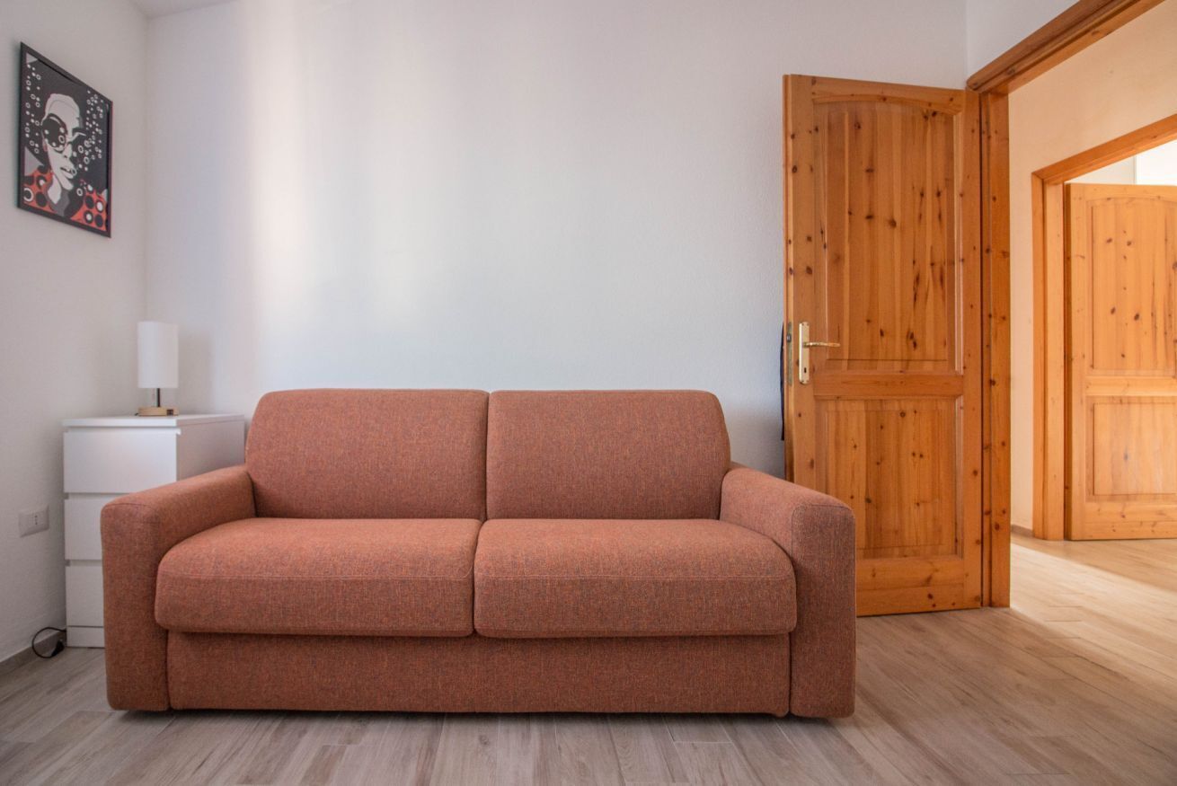 Et værelse med en sofa, en trædør og en hvid væg.