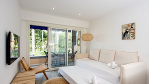 A bedroom with a bed, a sofa, a dining table, and a chair. There is a sliding glass door leading to an outdoor area. - Appartement Dollia - Welkeys (Cannes)