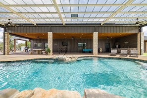 A covered outdoor pool area with a stone structure, seating, and a grill. - Perfect Couple’s Getaway in Luckenbach Tx Hot tub Pool (Fredericksburg)