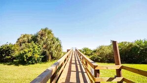 Eine Holzbrücke mit Geländern in einer grünen Umgebung mit Bäumen.