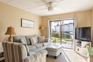 A living room with a sofa, ottoman, and a flat-screen TV.