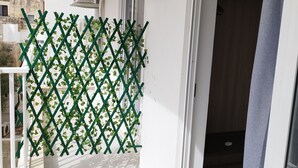 En balkon med et hvidt espalier, klimaanlæg og en skydedør, der fører ind i et rum.