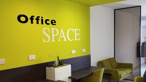 A modern office space with a bright yellow wall, a reception desk, and yellow chairs.