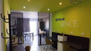 A modern office space with a bright green accent wall, a dining area, and a kitchen.