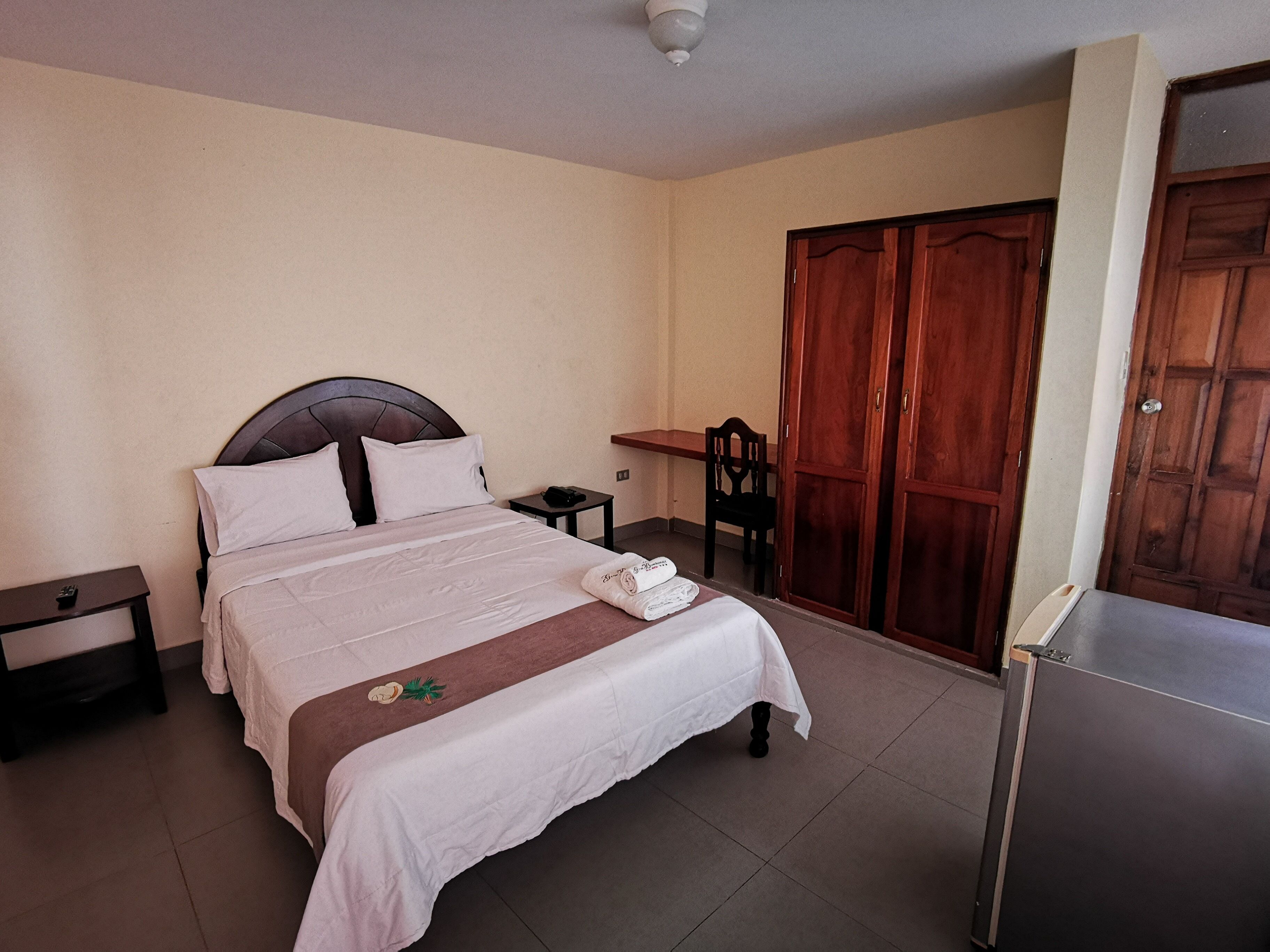 Un dormitorio con cama, mesita de noche, silla, armario y escritorio.