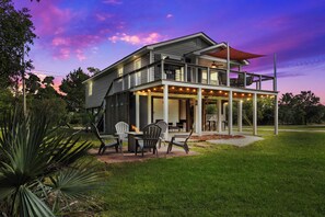 Une maison à deux étages dotée d’un patio couvert, d’un espace salon extérieur et d’un jardin aménagé.