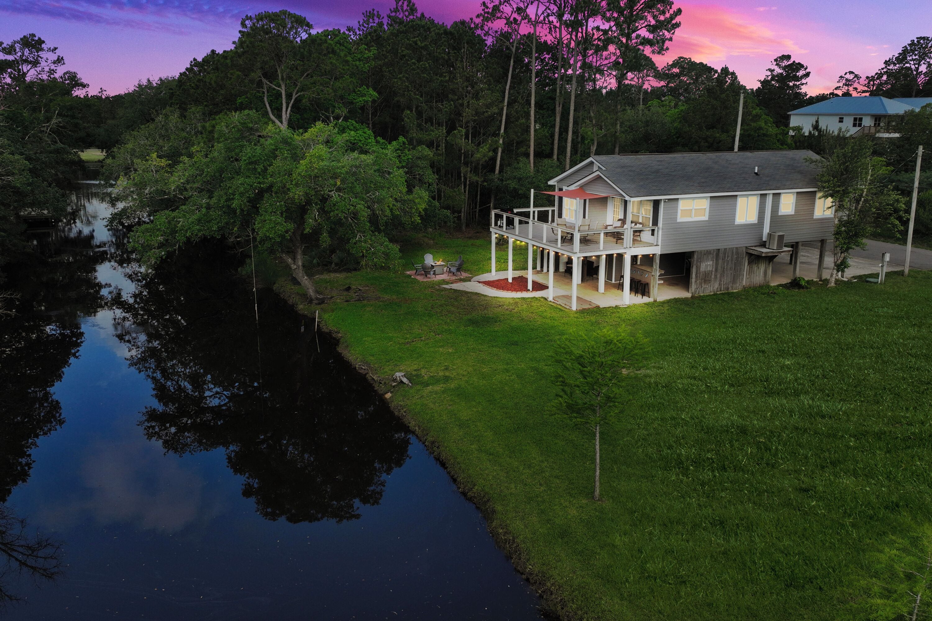A house with a porch, a small deck, and a pond in the backyard.
