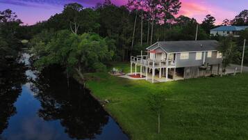 A house with a porch, a small deck, and a pond in the backyard.