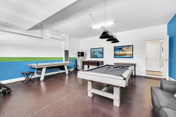 A pool table with a billiard cue, a pool table, and a pool table in a room with white walls and a blue accent wall. - Splendor Retreat| 6BR Villa w/ Kid's Room & Pool (Davenport)