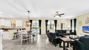 A spacious living area with a dining table, chairs, a sofa, and a TV. - Splendor Retreat| 6BR Villa w/ Kid's Room & Pool (Davenport)