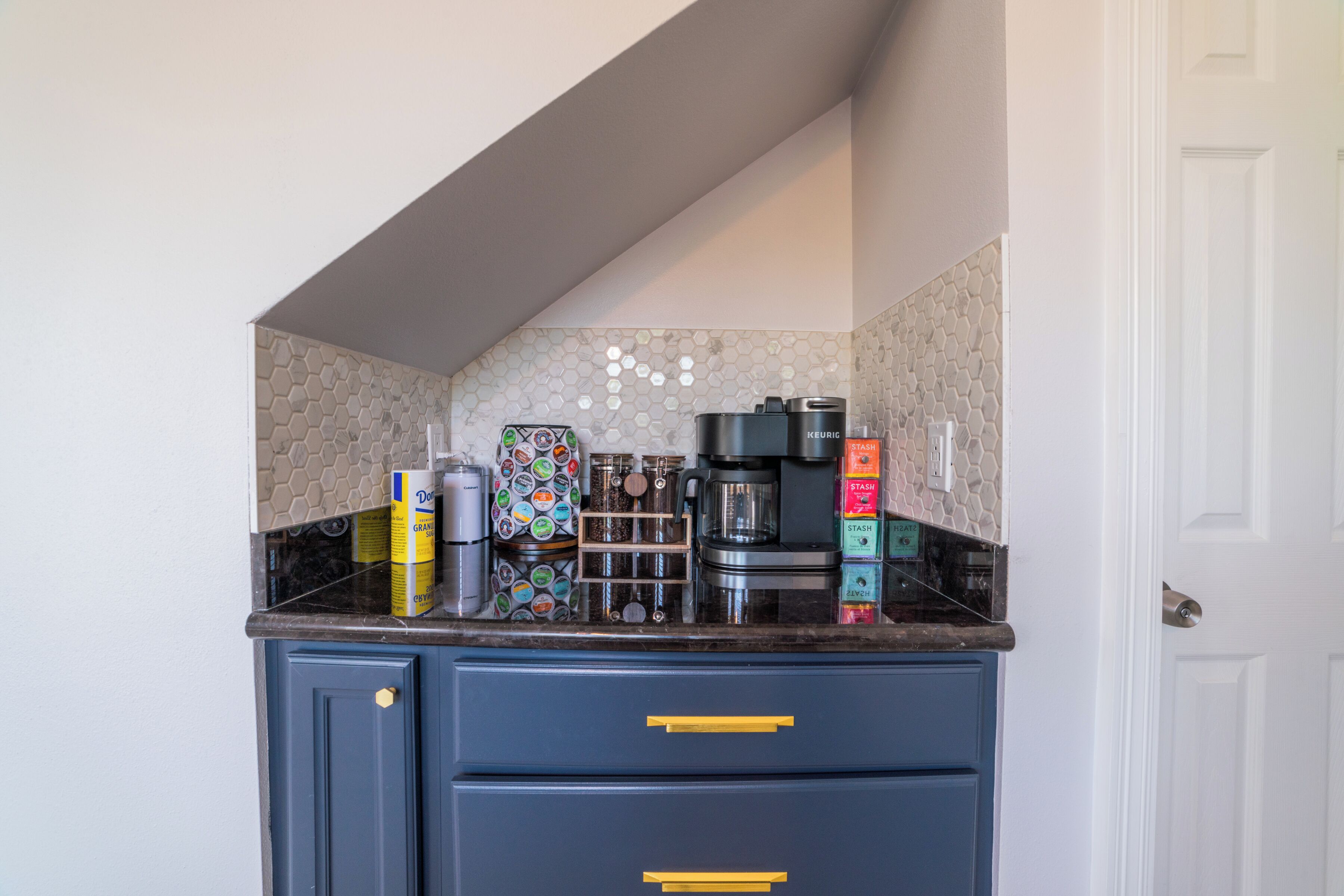 A kitchen with a coffee maker, tea kettle, and various containers on the counter.