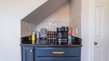 A kitchen with a coffee maker, tea kettle, and various containers on the counter.