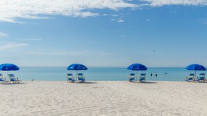 Une plage bordée de rangées de parasols bleus et de chaises de plage.