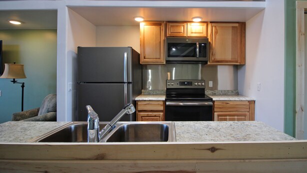 A kitchen with a stainless steel refrigerator, a microwave, and a stove.