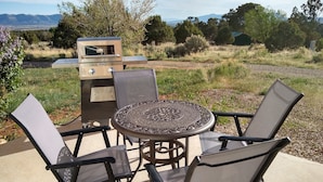 An outdoor patio with a grill, chairs, and a table.