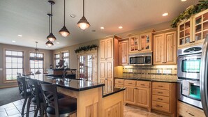A spacious kitchen with wooden cabinets, a central island with bar stools, stainless steel appliances, and pendant lighting. - Lake Miltona Family Vacation in the Alexandria Lakes area (Miltona)