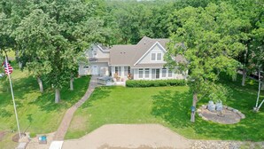 A two-story house with a large front lawn, a driveway, and a flagpole. - Lake Miltona Family Vacation in the Alexandria Lakes area (Miltona)