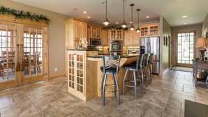 A spacious kitchen with wooden cabinets, a central island with bar stools, and modern appliances. - Lake Miltona Family Vacation in the Alexandria Lakes area (Miltona)