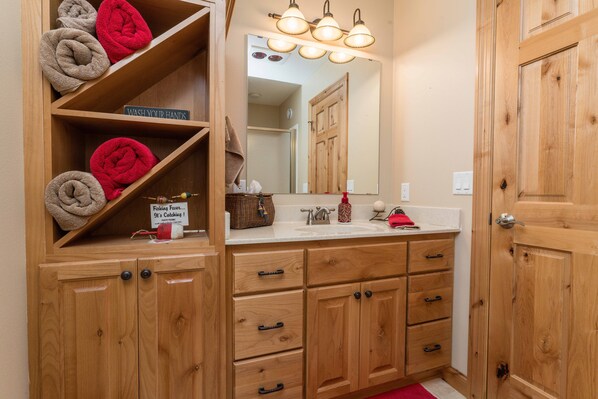 A wooden bathroom with a sink, mirror, and towel rack.