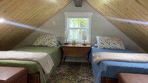 A cozy attic bedroom with two beds, a window, and a desk. - Clean, modern guesthouse located in a central Austin. (Austin)