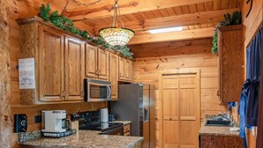A wooden cabin-style kitchen with a microwave, refrigerator, and granite countertops. - Eagle Lake Cabin Coalmont (Coalmont)